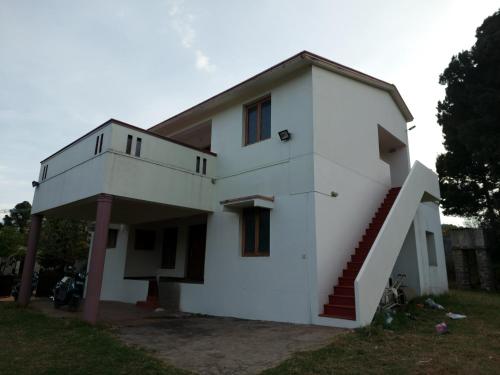 a white house with a staircase in front of it at Caron Niron Two Bedroom Villa in Kodaikānāl