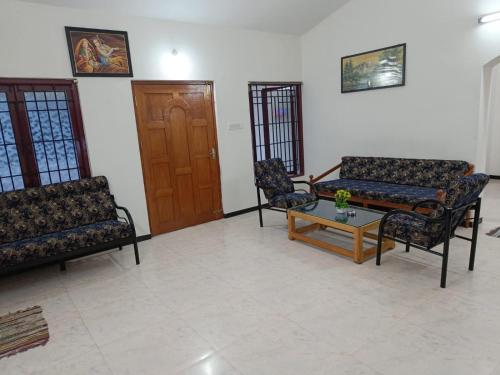 a living room with two chairs and a coffee table at Caron Niron Two Bedroom Villa in Kodaikānāl