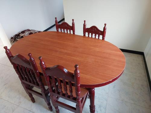 a wooden table with four wooden chairs around it at Caron Niron Two Bedroom Villa in Kodaikānāl