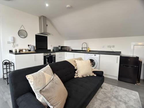 un salon avec un canapé noir dans une cuisine dans l'établissement Cosy 1 Bed Flat with Free Parking, à Birmingham