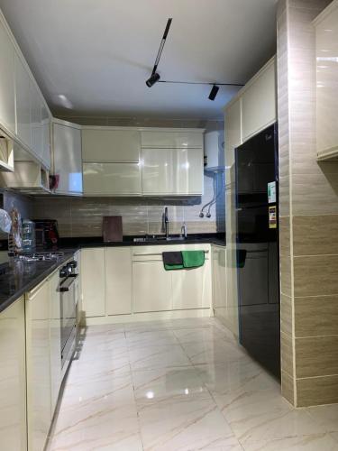 a kitchen with white cabinets and a black refrigerator at مدينتي in Madinaty