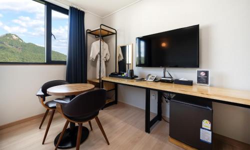 a room with a desk with a television and a table at CM Park Hotel in Andong
