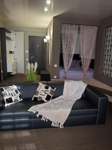 a living room with a black couch and a bed at CosHOME - apartament in Chişinău