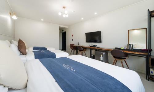 a hotel room with two beds and a desk at CM Park Hotel in Andong