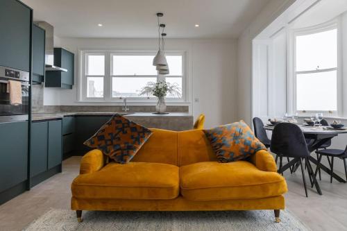 a living room with a yellow couch and a kitchen at Amazing Seaview - 2 bedroom, 2 bathroom in St. Leonards