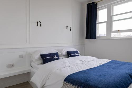 een bed met blauwe en witte lakens en een raam bij Amazing Seaview - 2 bedroom, 2 bathroom in St. Leonards