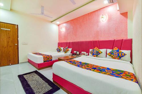 a bedroom with two beds and a pink wall at Hotel Avadh Palace RTO Circle Ahmedabad in Ahmedabad