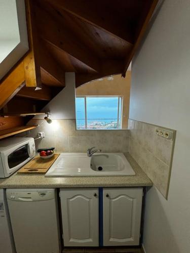 une cuisine avec un évier et un micro-ondes dans l'établissement T4 en duplex, vue mer et piscine, à Banyuls-sur-Mer