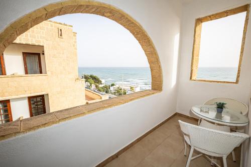 a room with an arch window and a table and chairs at La Rosa Hotel - Selinunte in Marinella di Selinunte