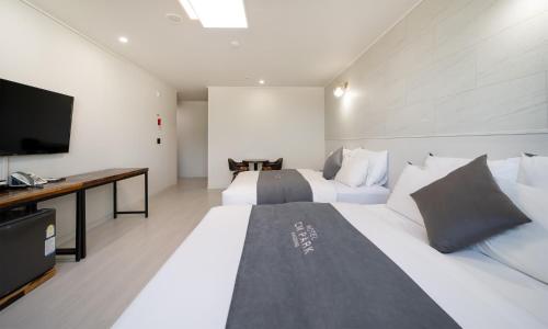 a bedroom with two beds and a desk and a television at CM Park Hotel in Andong