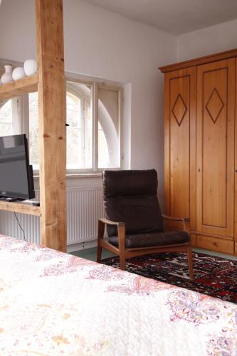 a bedroom with a bed and a chair and a tv at Grüne Villa in Bad Brambach