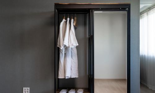 a wardrobe with white clothes hanging in a room at CM Park Hotel in Andong