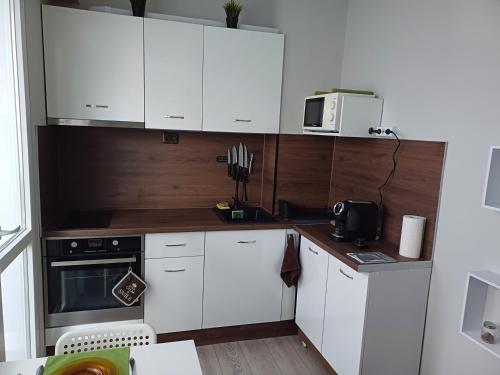 una pequeña cocina con armarios blancos y microondas en Maya's Airport Apartment en Sofía