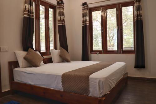 a bedroom with a large bed with windows at The Tree Lounge in Bhīm Tāl