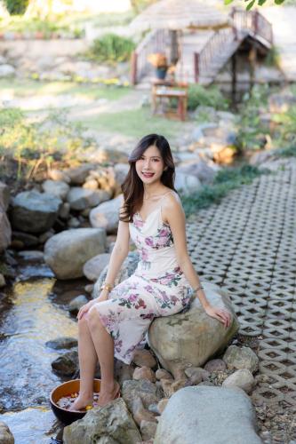 a woman in a dress sitting on a rock at Pupah Kanna Pua-ปู๋ ป๋าล์ คันนา ปัว in Pua