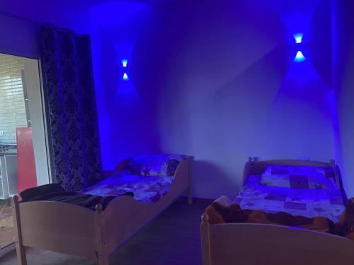 Luxury apartment with swimming pool view في مارينا سمير: سريرين في غرفة ذات إضاءة أرجوانية