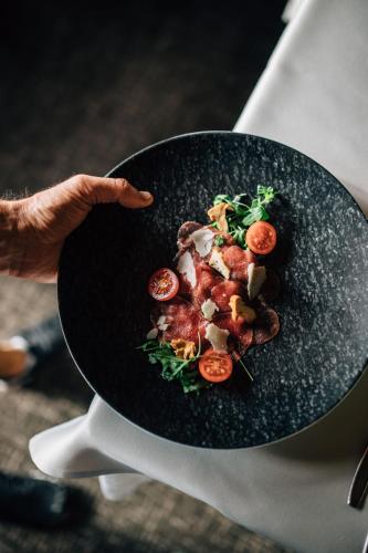 a person holding a black plate of food at Hotel Wildschütz in San Leonardo in Passiria