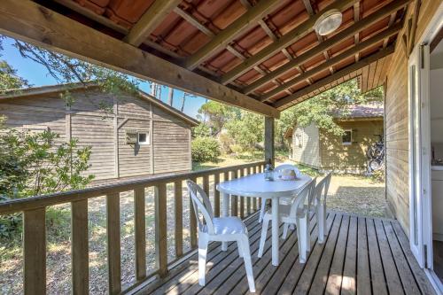 a patio with a table and chairs on a deck at Village Vacances La Forêt des Landes in Labenne