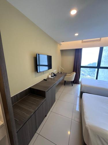 a hotel room with a tv and a bed and a desk at Grand Ion Delemen by 91 Homestay in Genting Highlands
