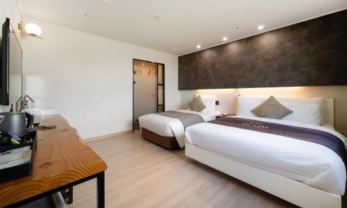 a hotel room with two beds and a desk at CM Park Hotel in Andong