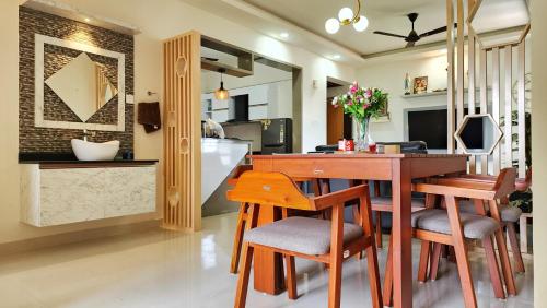 kuchnia i jadalnia z drewnianym stołem i krzesłami w obiekcie The soiree w mieście Thiruvalla