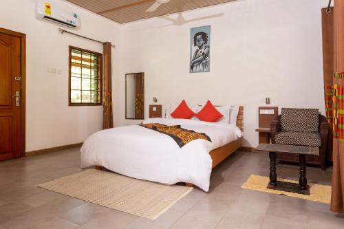 a bedroom with a large bed and a chair at Mekandi Riverside Resort in Akuse