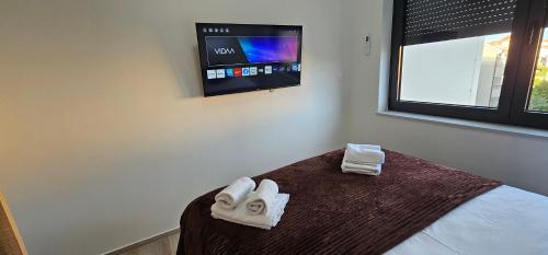 a bedroom with towels on a bed with a tv on the wall at Vila Ibrahimovic Vodice in Vodice