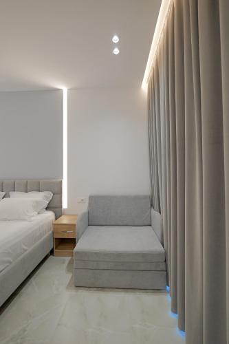 a bedroom with a bed and a chair next to a window at Vila Bana in Qeparo