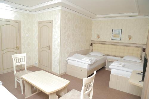 1 Schlafzimmer mit 2 Betten, einem Tisch und Stühlen in der Unterkunft URGANCH Hotel in Urganch