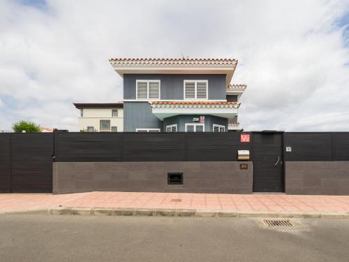 une maison derrière une clôture noire avec un bâtiment dans l'établissement Entire Home Meloneras BBQ Jacuzzi PoolGolf, à Meloneras
