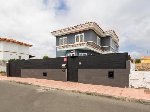 une maison avec une clôture noire en face d'une rue dans l'établissement Entire Home Meloneras BBQ Jacuzzi PoolGolf, à Meloneras