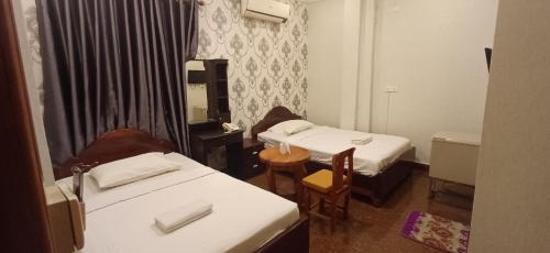 a small room with two beds and a table and chairs at Por Long guest house ផ្ទះសំណាក់ប៉ោឡុង in Phnom Penh
