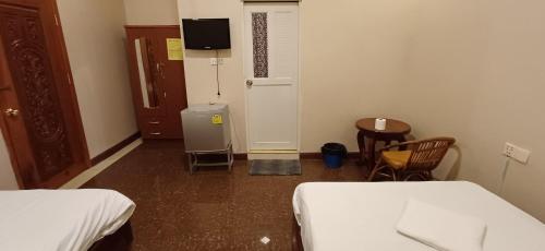 a small room with two beds and a table and chairs at Por Long guest house ផ្ទះសំណាក់ប៉ោឡុង in Phnom Penh