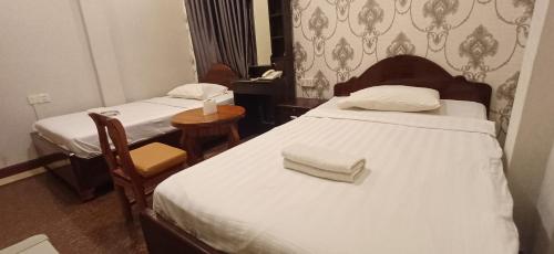 a bedroom with two beds and a table with a telephone at Por Long guest house ផ្ទះសំណាក់ប៉ោឡុង in Phnom Penh