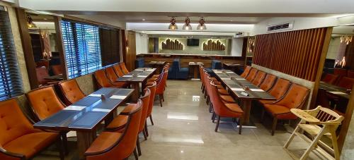 un ristorante con tavoli e sedie in legno in una stanza di HOTEL ARCHANA RESIDENCY a Mumbai