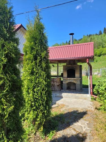 a pavilion with a red roof and a large bush at Карпатська Мавка in Vorokhta