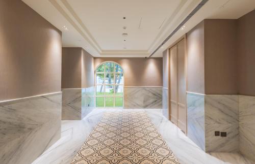 an empty hallway with marble floors and a large window at Enrise by Sayaji Lonavala in Lonavala