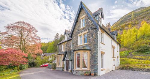 an old stone house with a car parked in the driveway at Thwaite Howe in Keswick