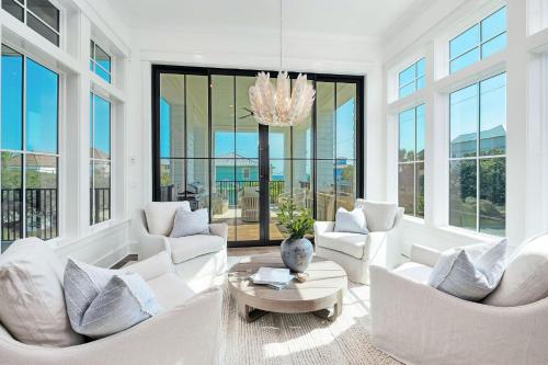 a living room with white furniture and large windows at Somewhere With You in Inlet Beach