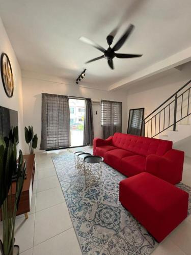 a living room with a red couch and a ceiling fan at D' Tambun Homestay Melaka in Melaka