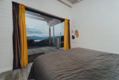 a bedroom with a bed and a large window at Fanarele din Hangu in Hangul