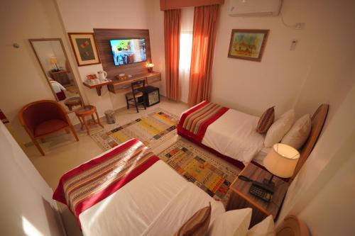 a view of a bedroom with two beds and a desk at Petra Plaza Hotel in Wadi Musa