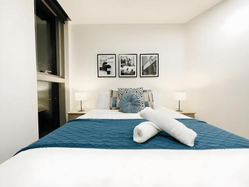 een wit bed met blauwe lakens en kussens erop bij Mega Style Apartments Kings Domain in Melbourne