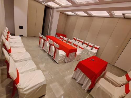 a room with red and white chairs and tables at J Hotel and Banquets in Mumbai