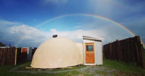 una gran tienda de campaña en la cúpula con un arco iris en el cielo en Waipu Off-grid Eco Geodesic Glamping Dome en Waipu