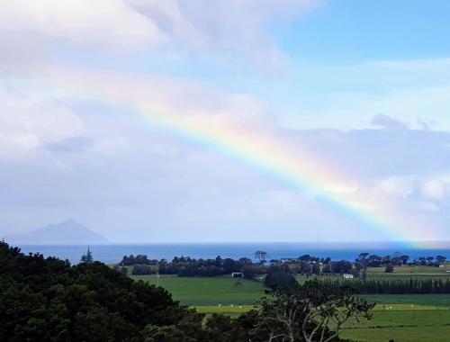 un arco iris en el cielo sobre el océano en Waipu Off-grid Eco Geodesic Glamping Dome, en Waipu