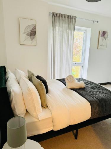 a bed with white pillows and a window in a room at Luxurious & Spacious 2 Bed Apartment- Private Parking in Kent