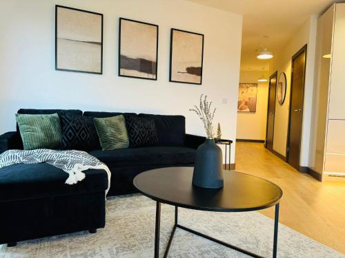 a living room with a black couch and a table at Luxurious & Spacious 2 Bed Apartment- Private Parking in Kent
