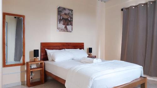 ein Schlafzimmer mit einem großen weißen Bett und einem Spiegel in der Unterkunft Les Manglier in Port Mathurin