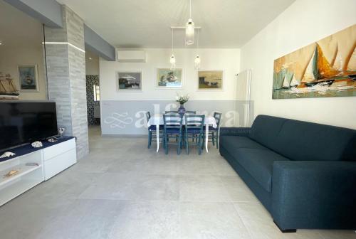 un soggiorno con divano blu e tavolo di MAYFLOWER terrazza vista mare e posto auto a 50 metri dal mare a Castiglione della Pescaia